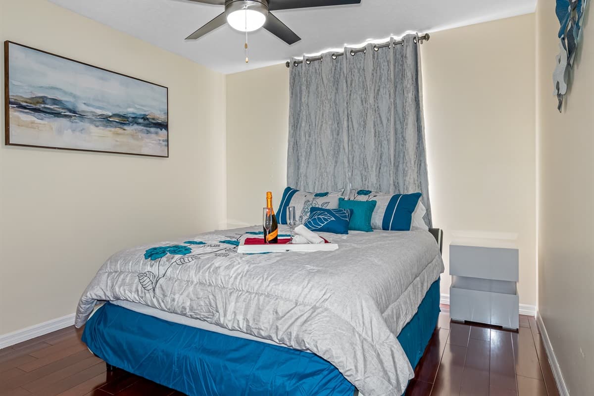 On the left side of the bed, is a white bedside table providing a convenient and stylish spot for the night lamp, books, and other bedtime essentials.