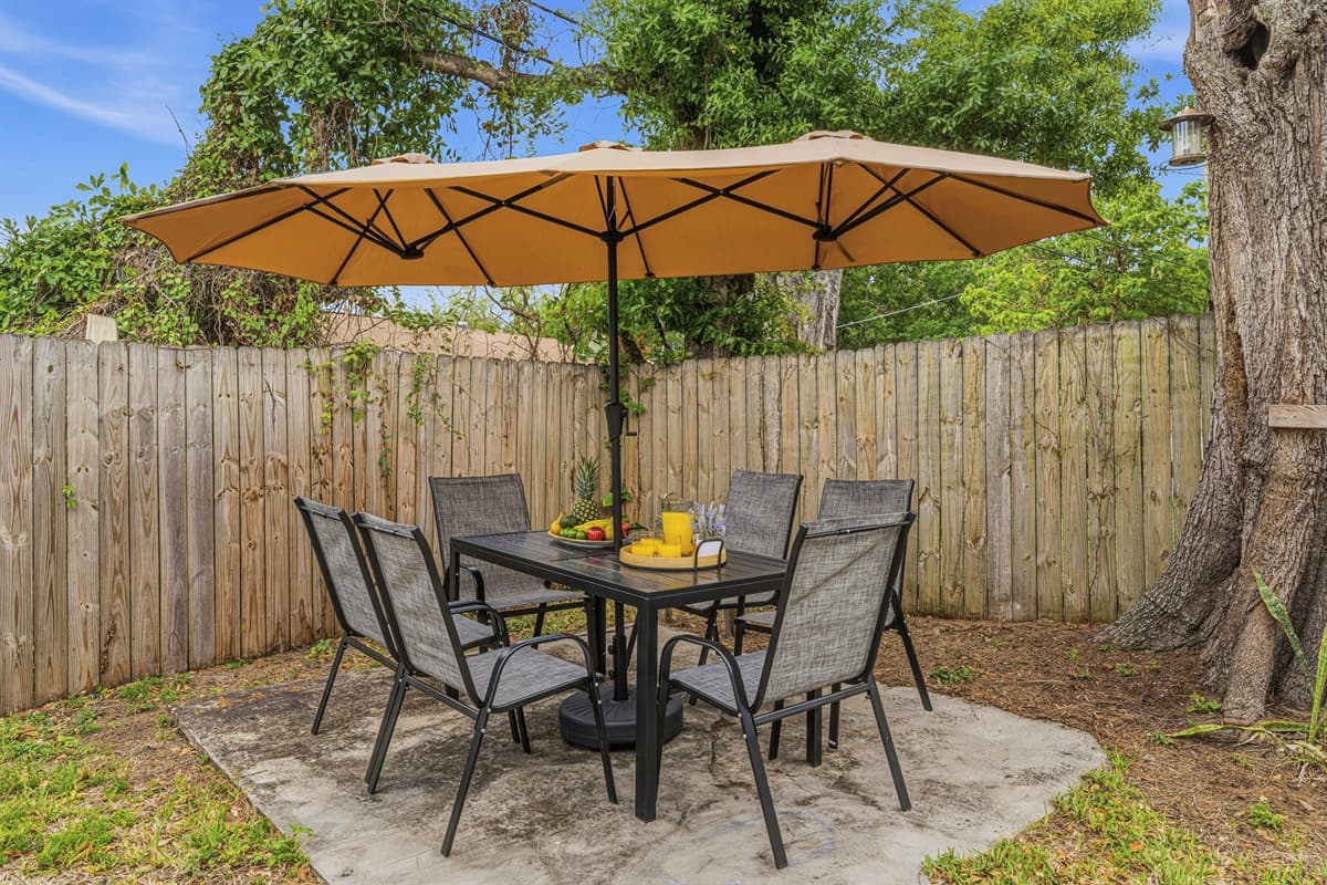 Private backyard patio featuring outdoor dining, umbrella shade, and fenced yard—ideal for meals or evening relaxation.