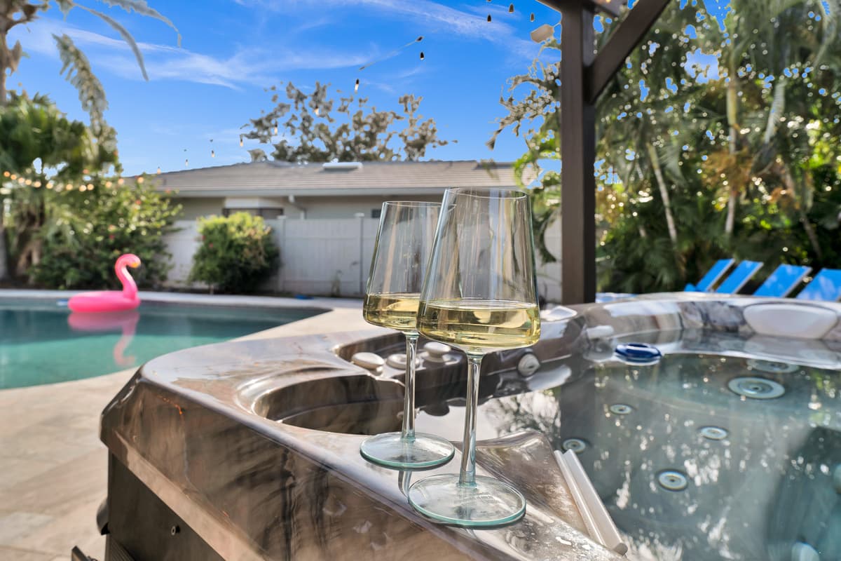  Two chilled glasses of wine rest beside the private hot tub, string lights overhead promising a romantic evening soak