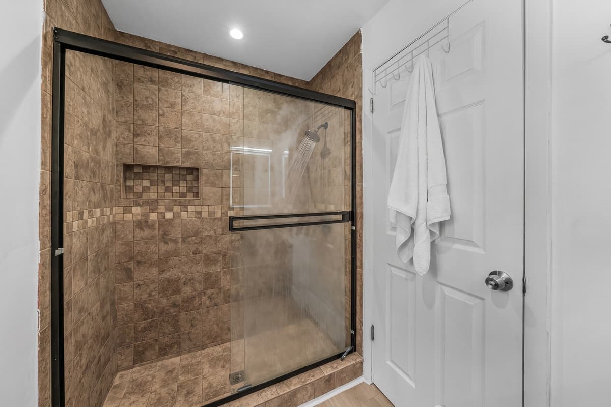 Glass shower doors, quality finishes, and a framed mirror elevate this space above the average rental bath.