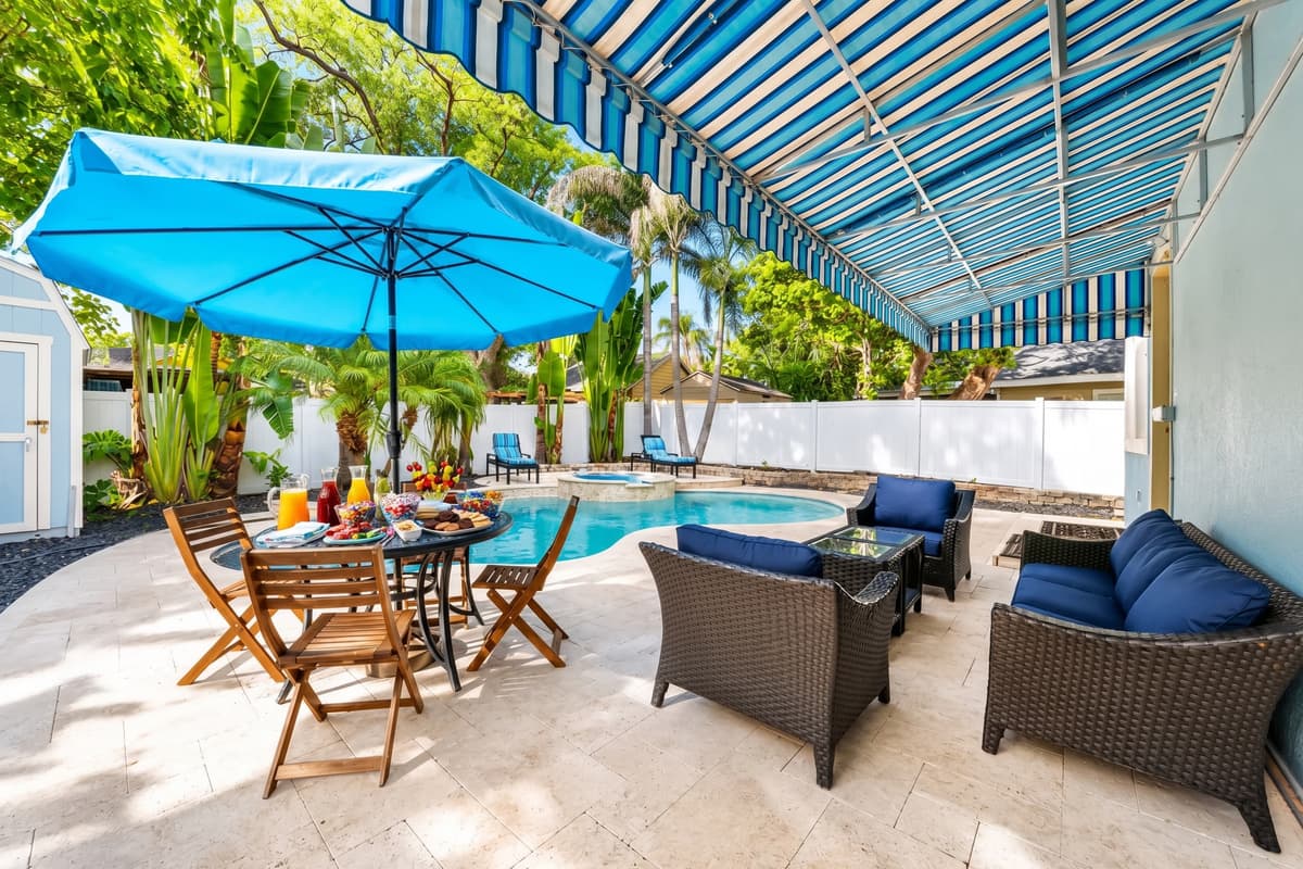 Enjoy outdoor dining and lounge seating under the shaded patio, perfect for relaxing by the pool.
