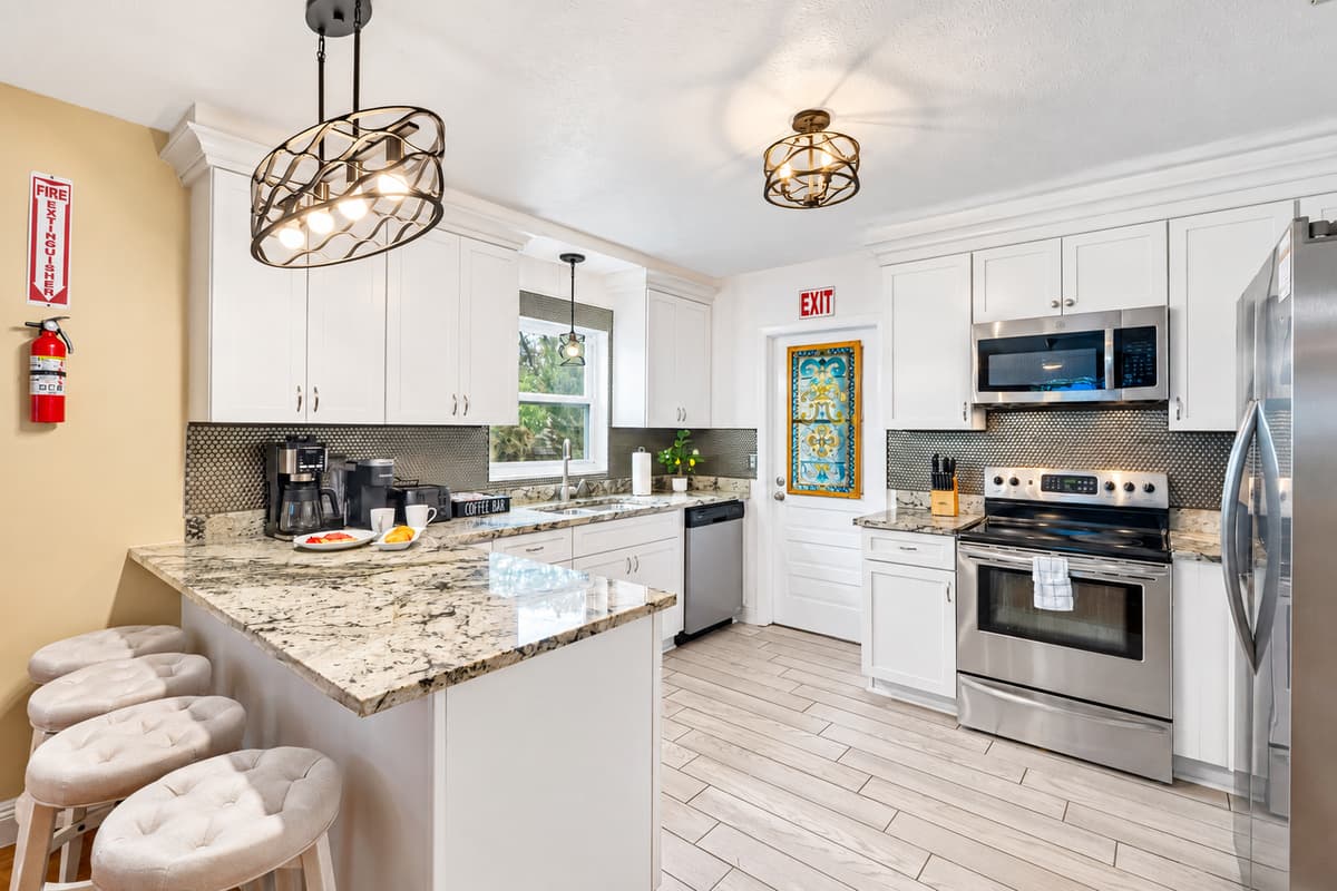 Bright, modern kitchen with white cabinetry, granite countertops, and stainless steel appliances.
