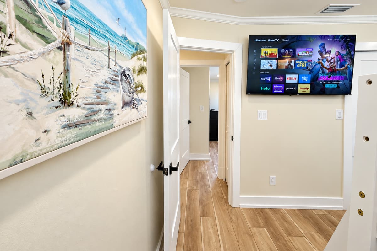Queen bedroom with a white metal bed frame and smart TV.