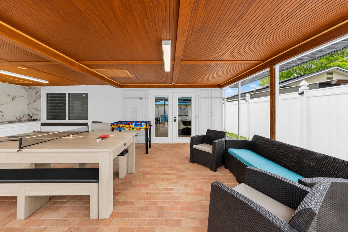 Relax and unwind in the spacious covered outdoor living area, complete with lounge seating, games, and plenty of space for making memories with family and friends.
