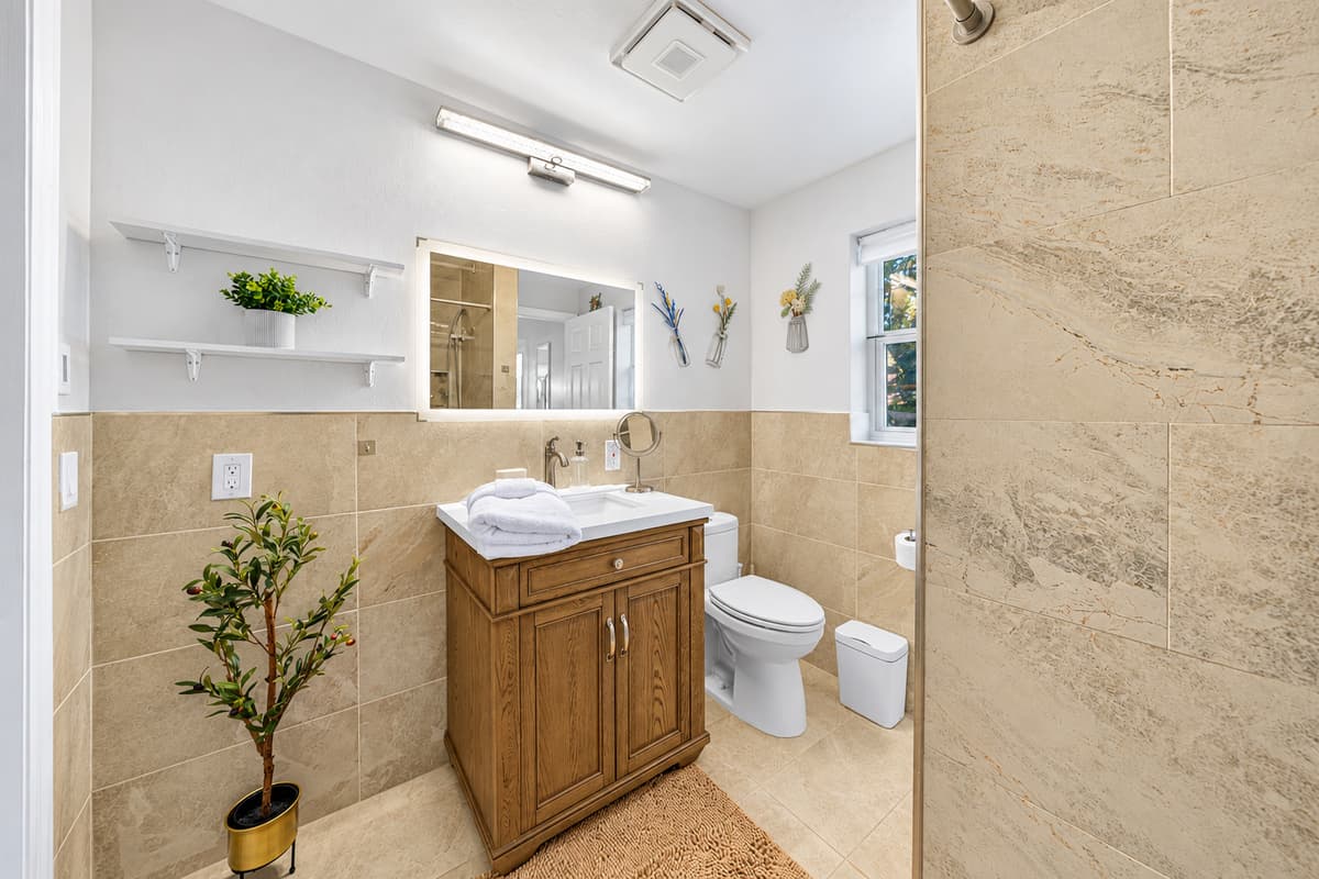 The bathroom feels luxurious and open, highlighted by a walk-in shower and stylish stone-inspired tile.