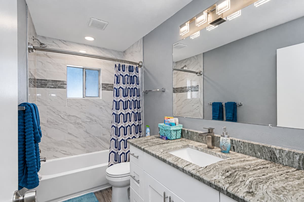 This bathroom has a bathtub, sink, toilet, shower, and wide vanity mirror. Have long baths after long days of fun activities with loved ones! If you like what you see, send us an inquiry!