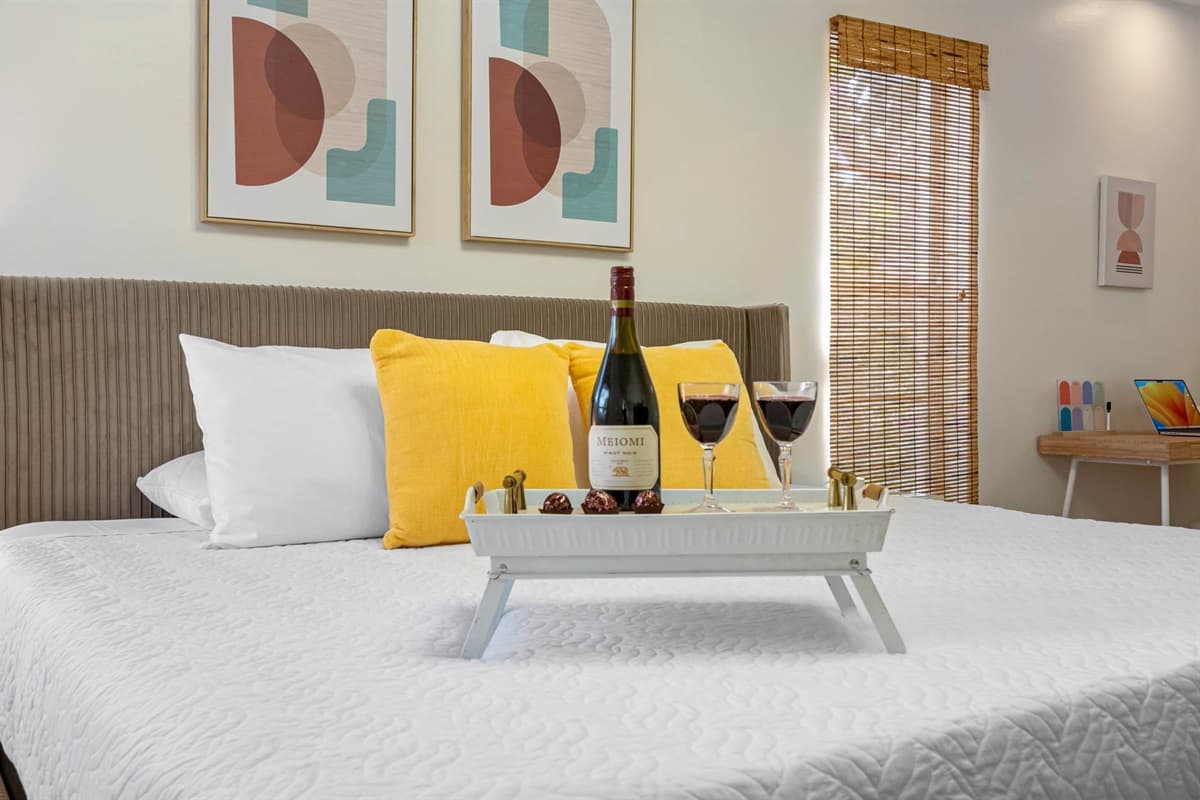 Wake up to soft filtered light through natural woven shades in this inviting bedroom. A king-sized bed, stylish decor, and ensuite bathroom offer all the comfort and privacy you need.