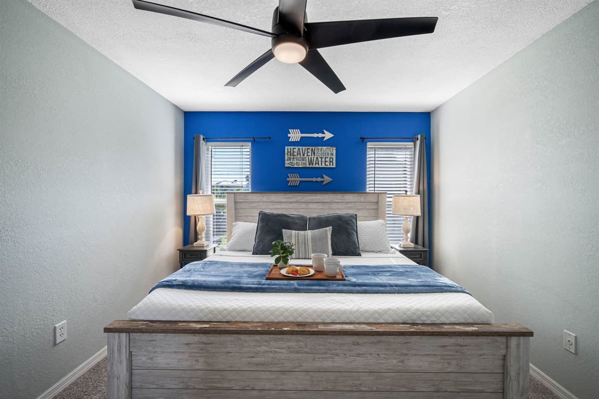 A spacious bedroom with a king bed, modern ceiling fan, and cozy carpet flooring for extra comfort.