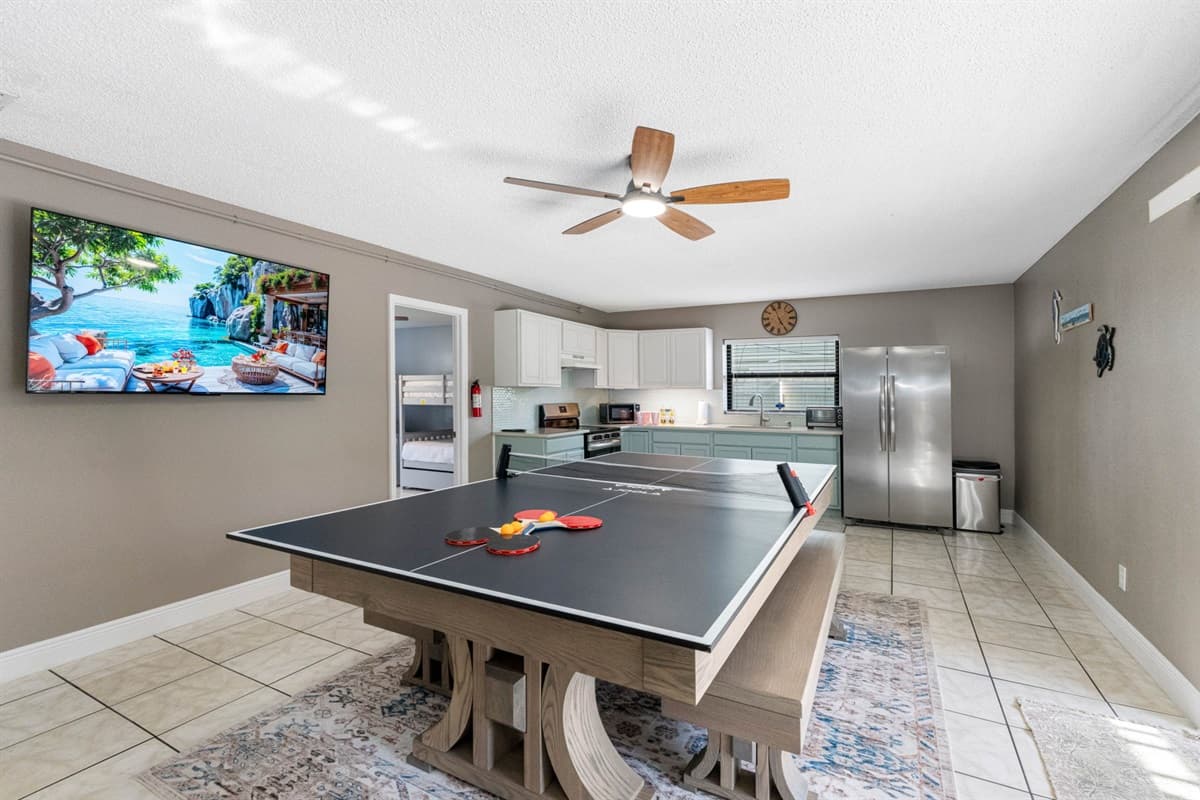 At the center of the room is a modern farmhouse-style table that transforms effortlessly from a dining space to a full-size ping pong table.