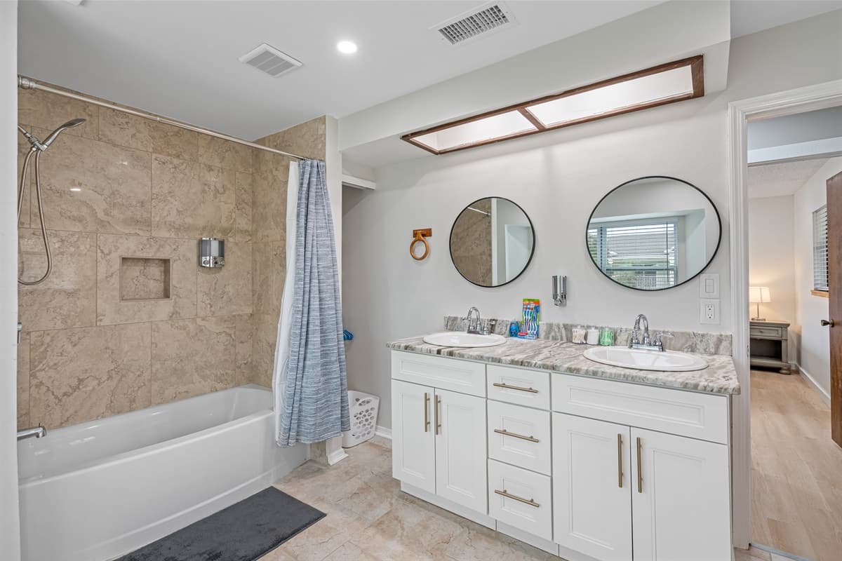 Indulge in the ultimate comfort and luxury of our exquisite bathroom, complete with a delightful combination of a tub and shower, elegant his and her sinks, and a modern toilet.