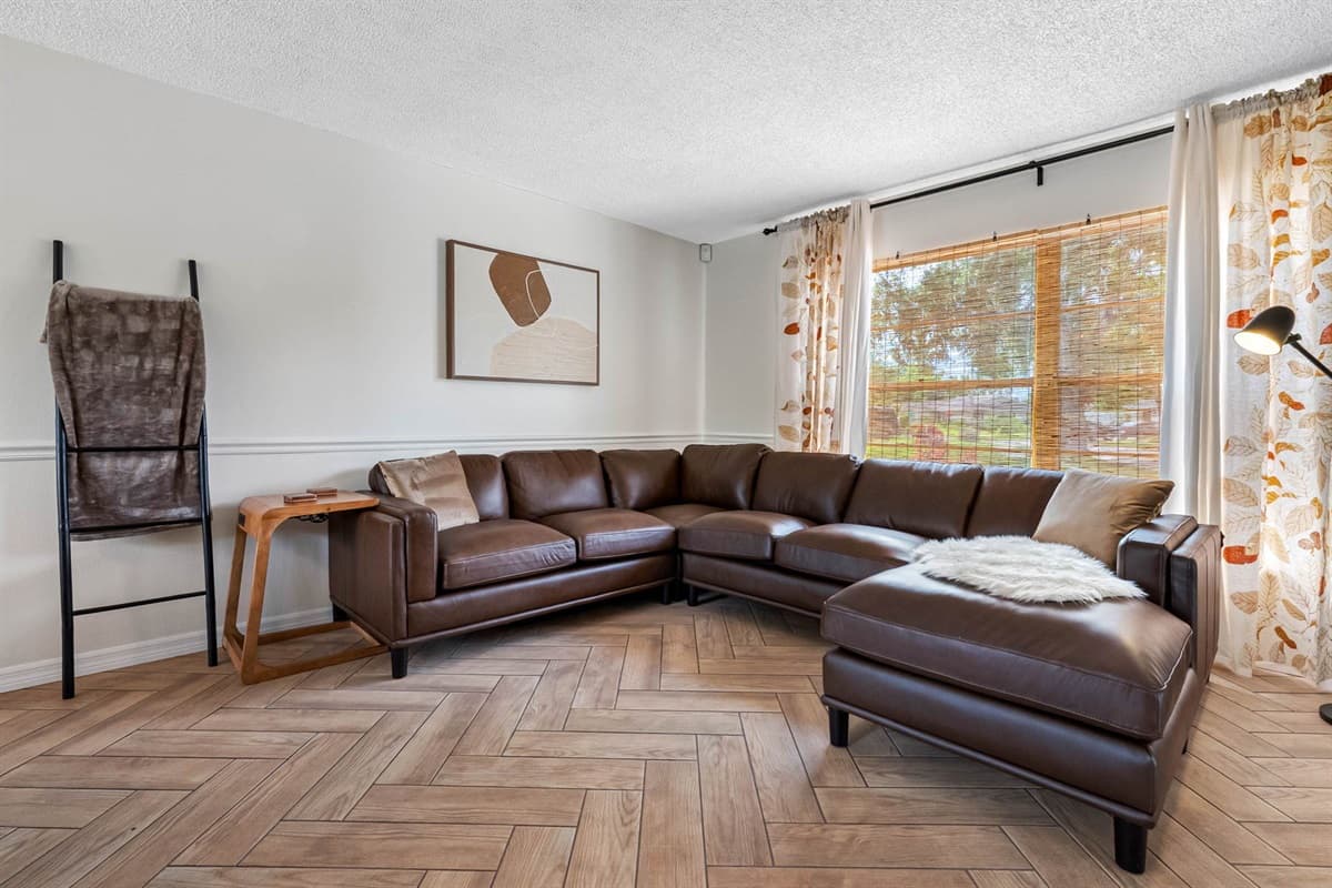 From the soft leather sectional to the artistic accents and statement decor, this living room was designed for pure comfort. The TV setup is ideal for streaming, and the flow to the dining area makes entertaining a breeze.