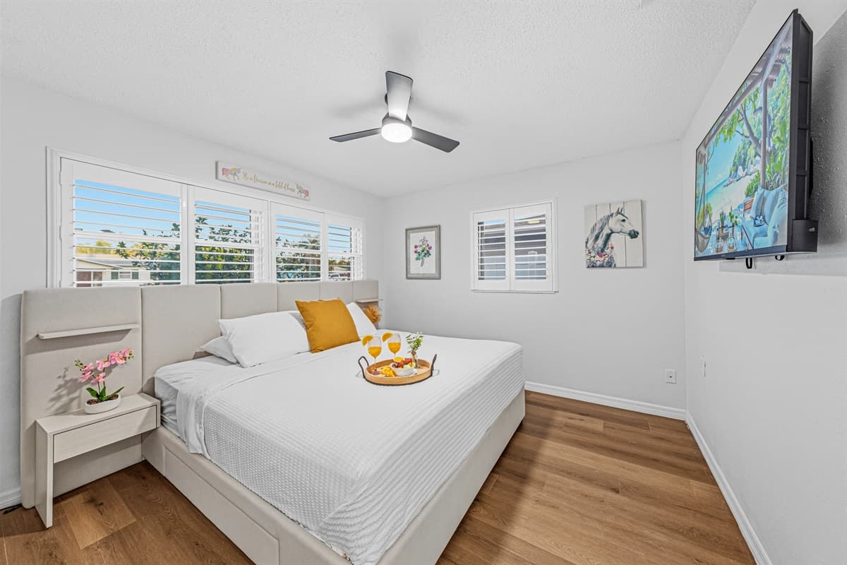 Spacious king bedroom with TV, soft lighting, and a comfortable layout for restful nights 
Tray and food setup shown are for staging purposes only and are not included.