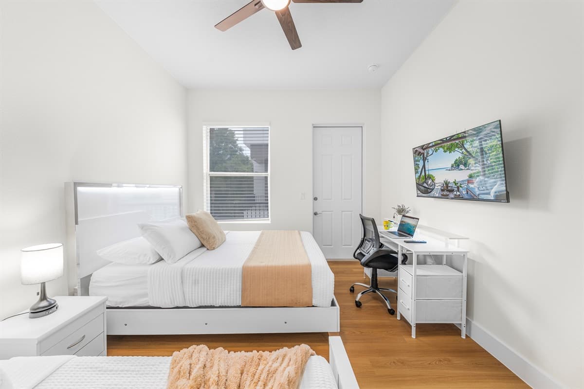 Your own private suite with a queen bed, twin bed, wall-mounted Smart TV, and a full work desk. Sleep, stream, or work — your call.