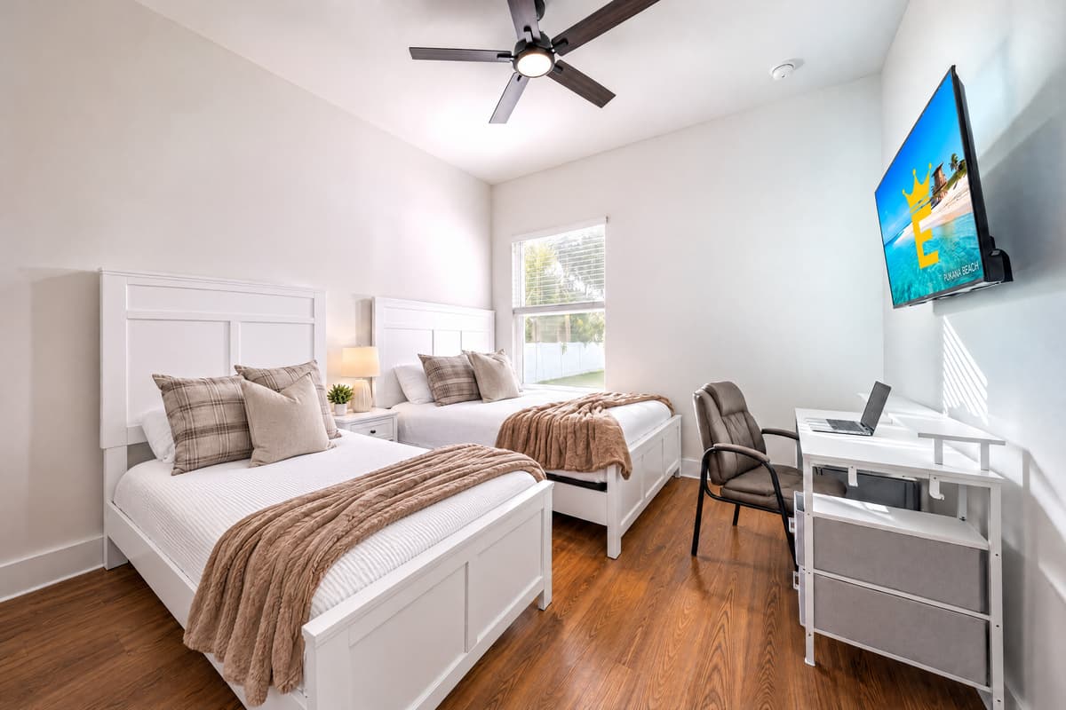 Bright bedroom with ceiling fan, blackout-ready blinds, and a workspace that doesn't feel like an afterthought