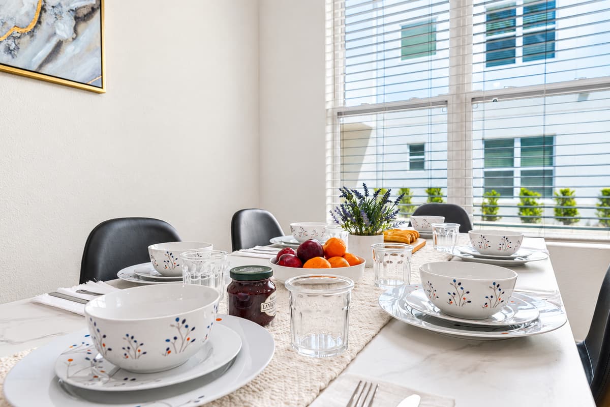 Beautifully set dining table near large windows with natural light.