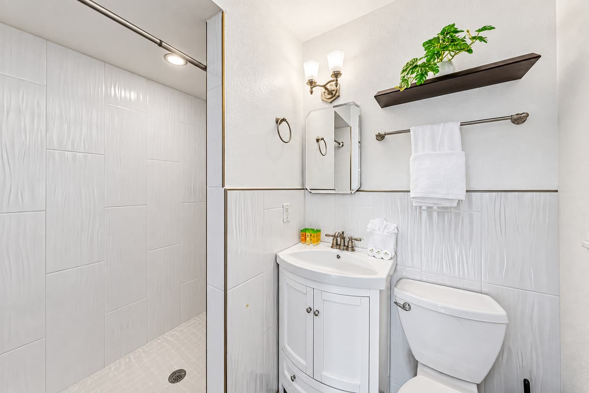 Clean and modern bathroom with walk-in shower, fresh white finishes, and essential amenities 