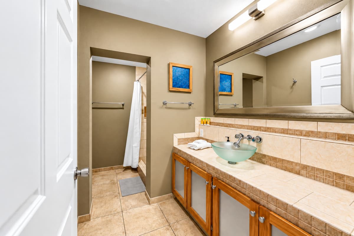 Bright and functional bathroom with a modern glass vessel sink, large mirror, and ample counter space.