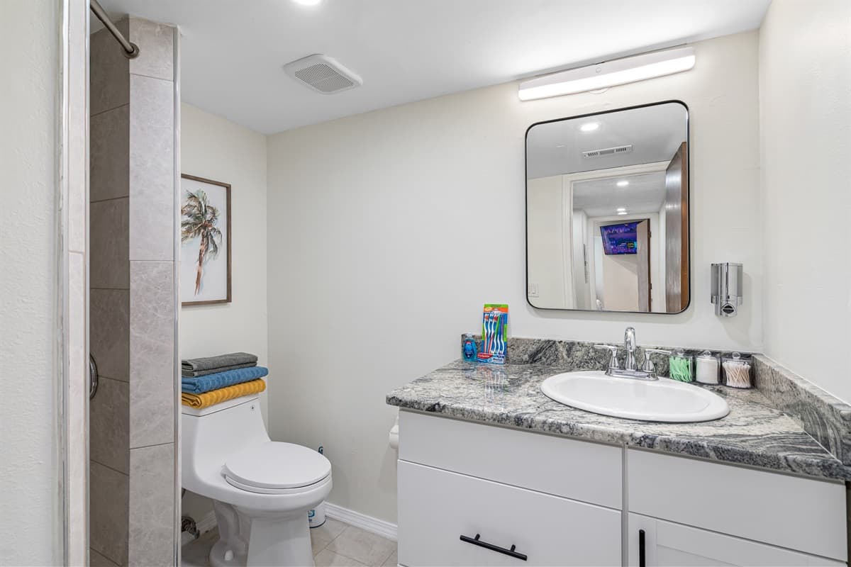 The sink is accompanied by a well-lit mirror, offering the ideal space for your morning routine or evening skincare rituals.
