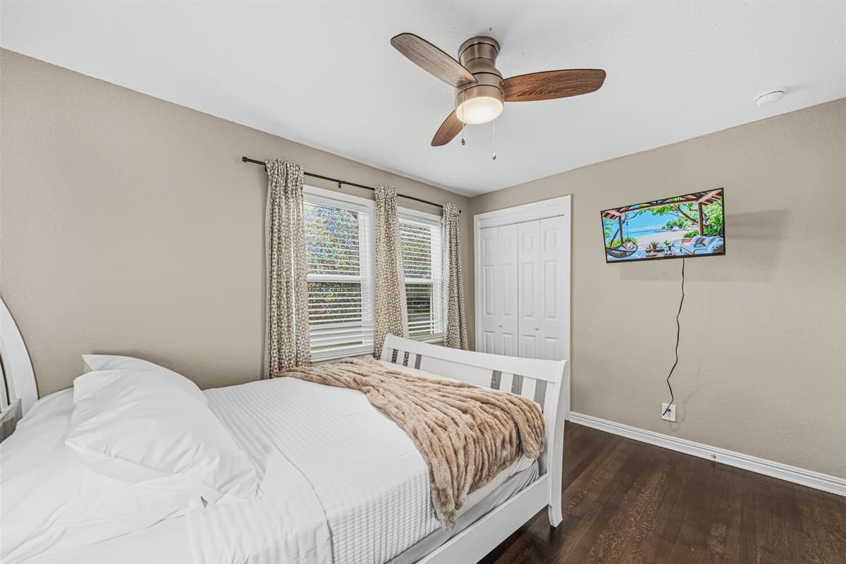 Bright bedroom featuring a comfy bed, wall-mounted TV, and large windows for a relaxing retreat.