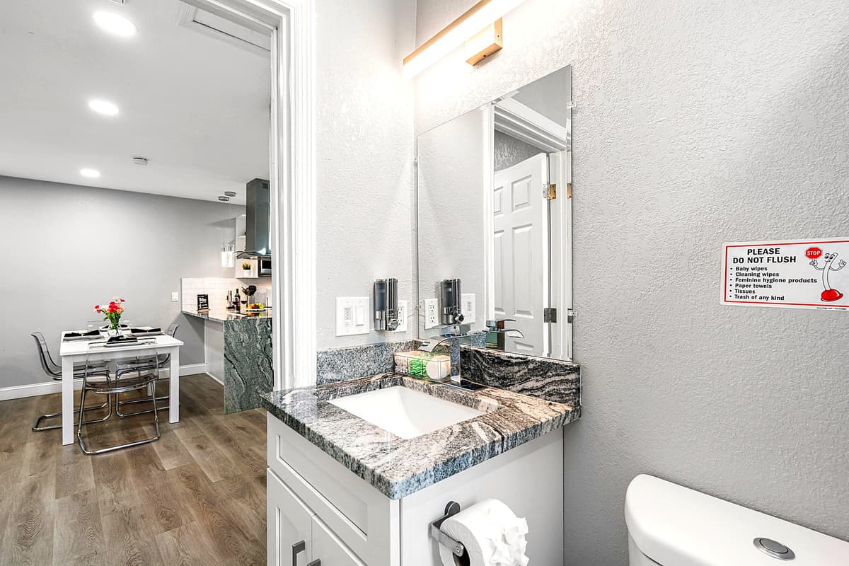 The vanity, topped with a polished marble countertop, provides ample space for all your toiletries and features a large mirror that enhances the room's brightness and spaciousness.