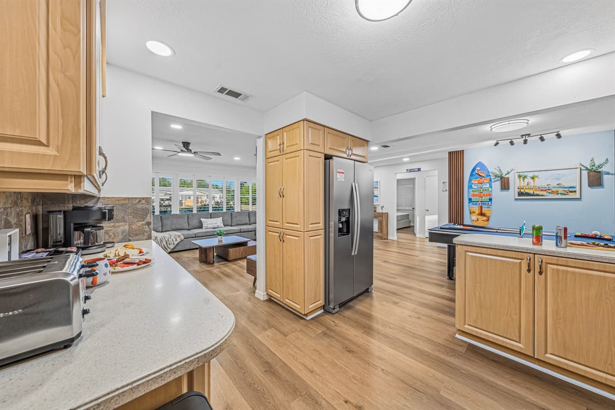 Open kitchen layout with bar seating and seamless flow into the living and game areas 
