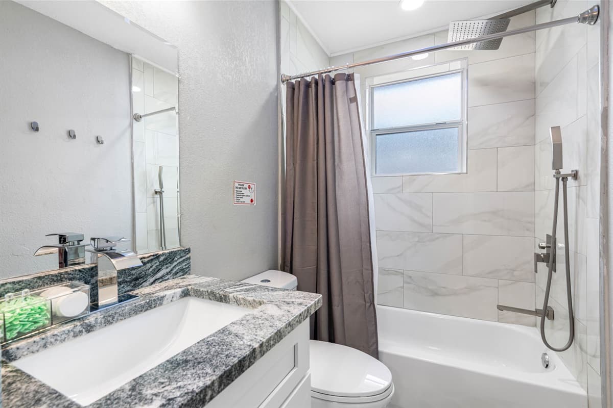 Bathroom with modern tub/shower combo, sleek fixtures, and clean tile finishes.