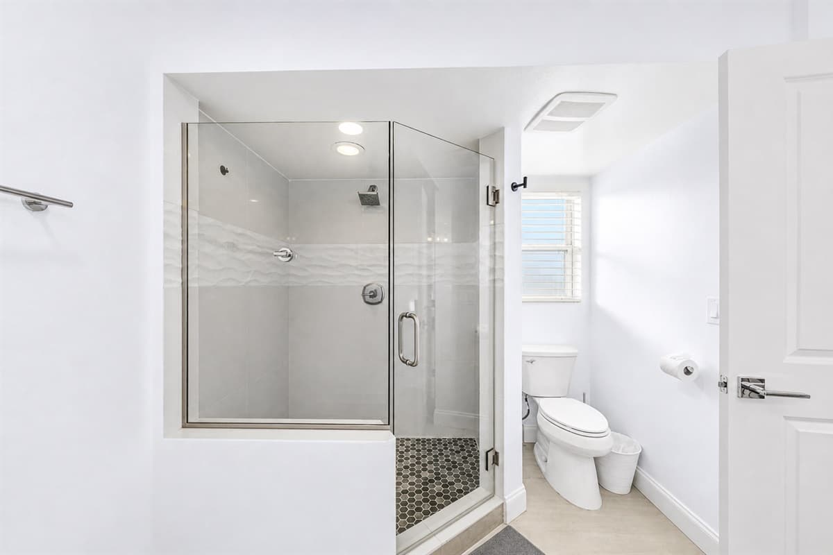 Private walk-in shower with glass enclosure and bright natural lighting.