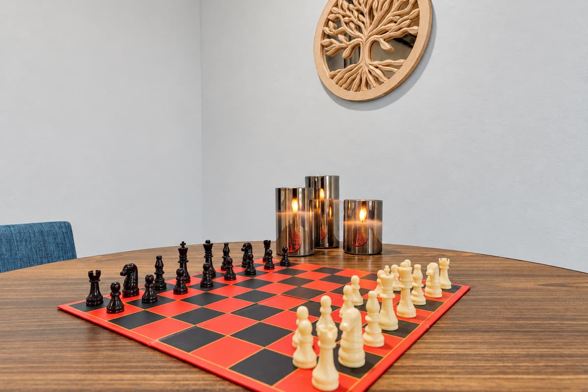 Somebody always starts a game by night two. Full-size chess set out and waiting, in a quiet corner — the reason the evening keeps going long after the pool lights come on.