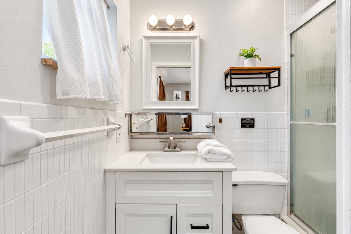 This bathroom features crisp white finishes, a sleek vanity, and bright lighting, creating a fresh and modern feel.
