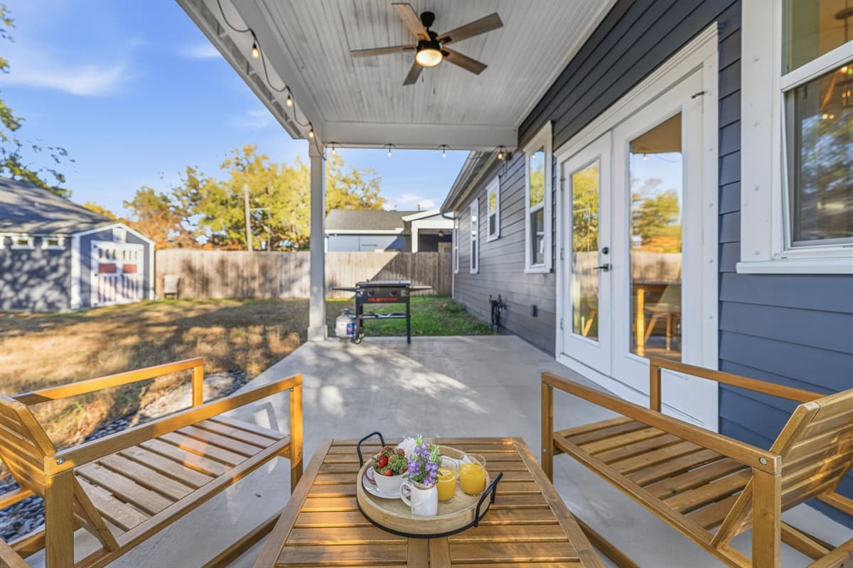 Resort vibes at home — this covered side deck features rich hardwood decking, ceiling fan, and built-in seating with a tray ready for drinks. Brand-new construction with outdoor living spaces designed to impress.