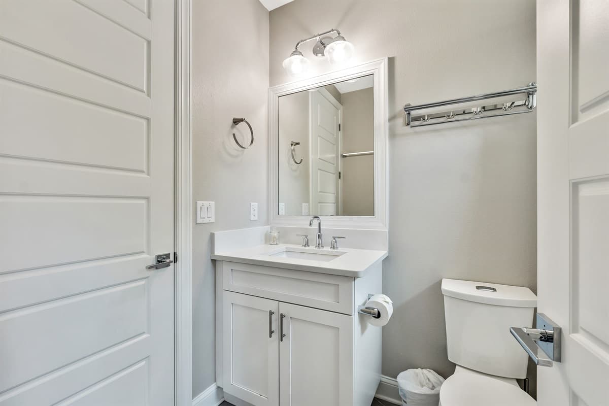 Soft, ambient lighting from overhead fixtures and vanity lights creates a warm and inviting atmosphere, ideal for unwinding after a long day.
