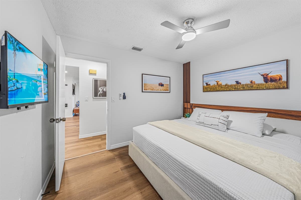 Large king bedroom featuring wall-mounted TV, modern décor, and plenty of open space to relax 