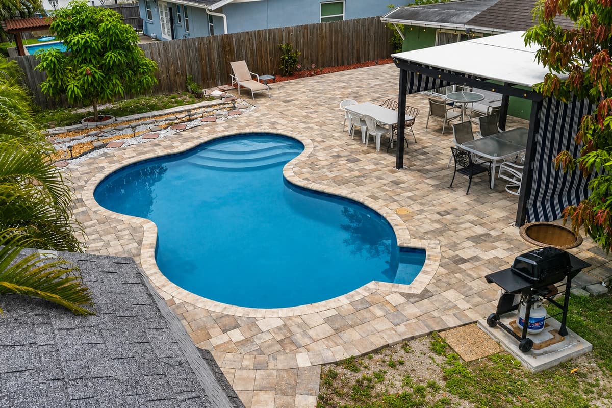 Bird’s-eye view showcasing the private pool, covered patio, outdoor dining, and spacious backyard.