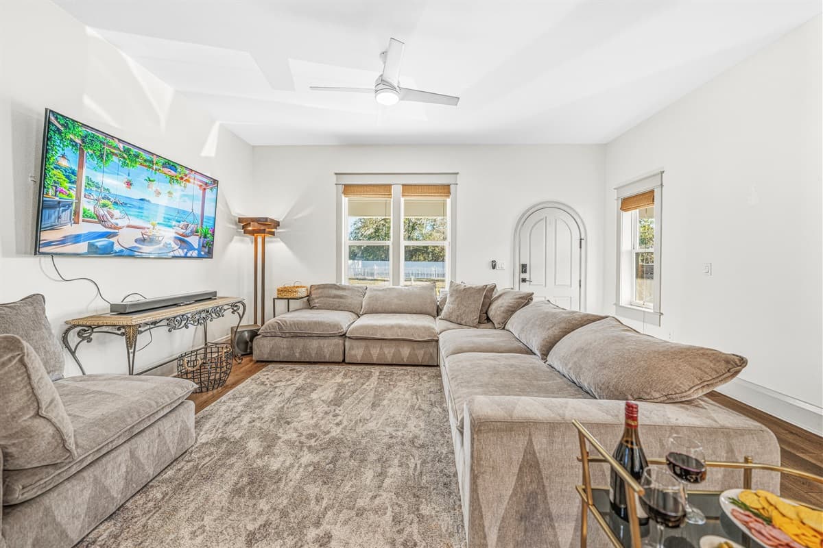 Bright and airy living room with soaring ceilings, ceiling fan, smart TV, and the signature arched doorway that runs throughout this gorgeous brand-new Seminole Heights home. Light pours in from every angle.
