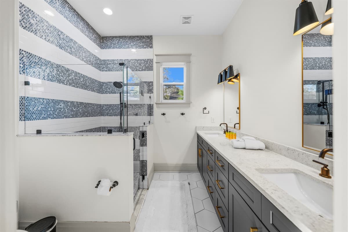 Brand-new master bathroom with a stunning double vanity, navy cabinets, white quartz counters, gold fixtures, backlit mirror, and a walk-in tiled shower. Pure luxury in the heart of Seminole Heights, Tampa.