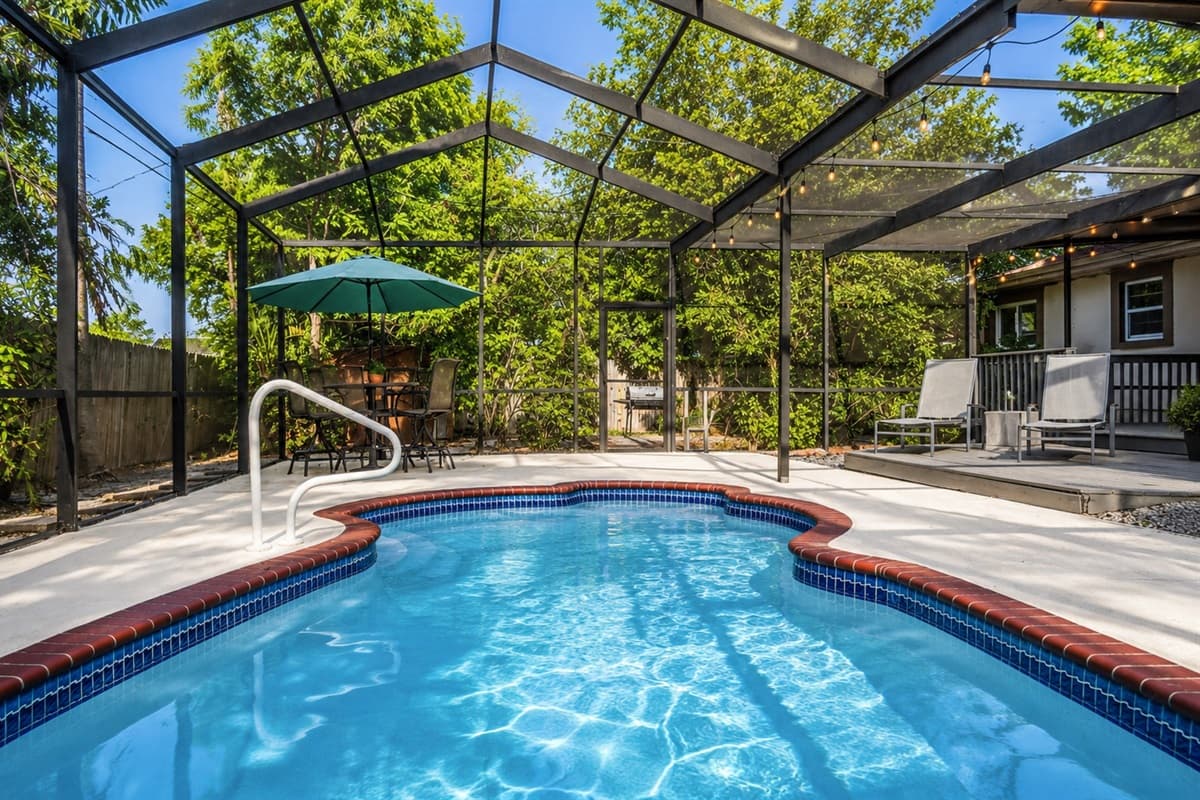 Refreshing screened-in pool surrounded by lush greenery and plenty of outdoor seating.