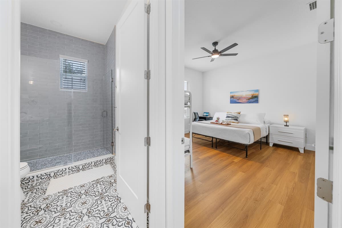 A designer walk-in shower with subway tile and glass door connects to the bedroom — luxury you'd expect from a five-star hotel.