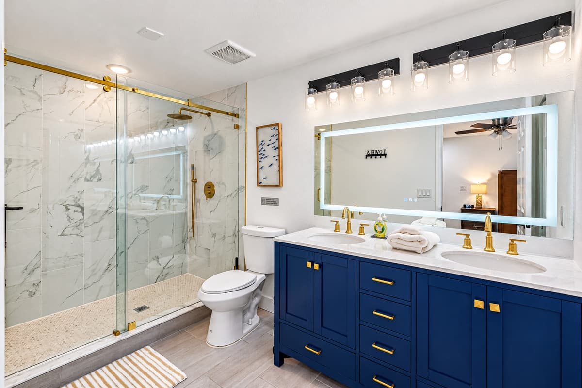 Bedroom 1 - Ensuite: This bathroom boasts a sleek navy double vanity, gold fixtures, and a walk-in glass shower that feels like a 5-star hotel.