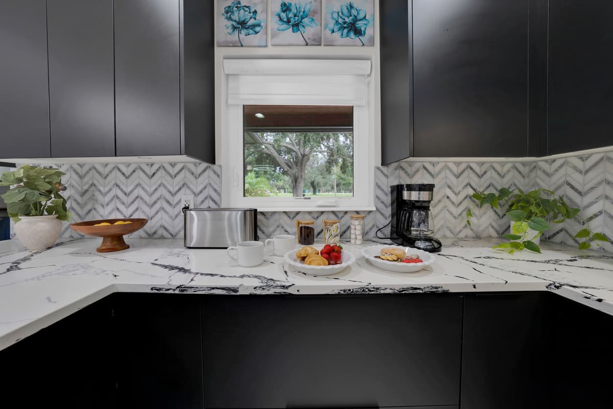 Nothing feels accidental in this kitchen — matching greenery, matching art, a centered window pulling both halves into one balanced scene.
