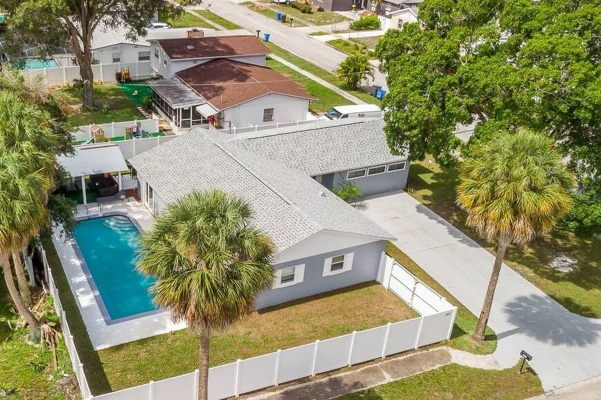 Aerial back view of our beautiful house showcasing our stunning heated pool. The property has some trees and has a fenced backyard. If you are interested in this property, send us an inquiry now!