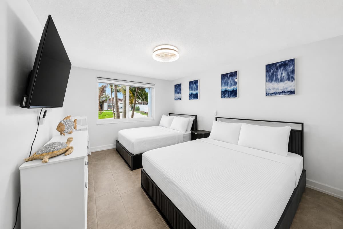 Spacious bedroom featuring a comfortable king bed, a queen bed, a wall-mounted Smart TV, and plenty of natural light for a relaxing stay.