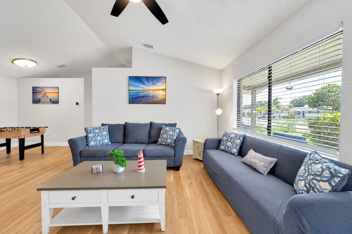 The long window keeps this room bright until late afternoon, and the sofas face each other instead of the screen. Sit here after the pool and the conversation runs longer than anybody planned it to.