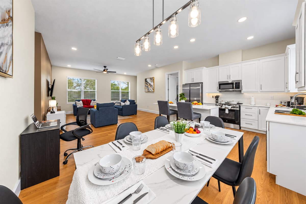 Where every group dinner becomes a memory. Warm pendant light over a table set for the whole crew, the kitchen steps away, the living room in view. Cook, serve, and linger: nobody misses a story while dinner is on the table.