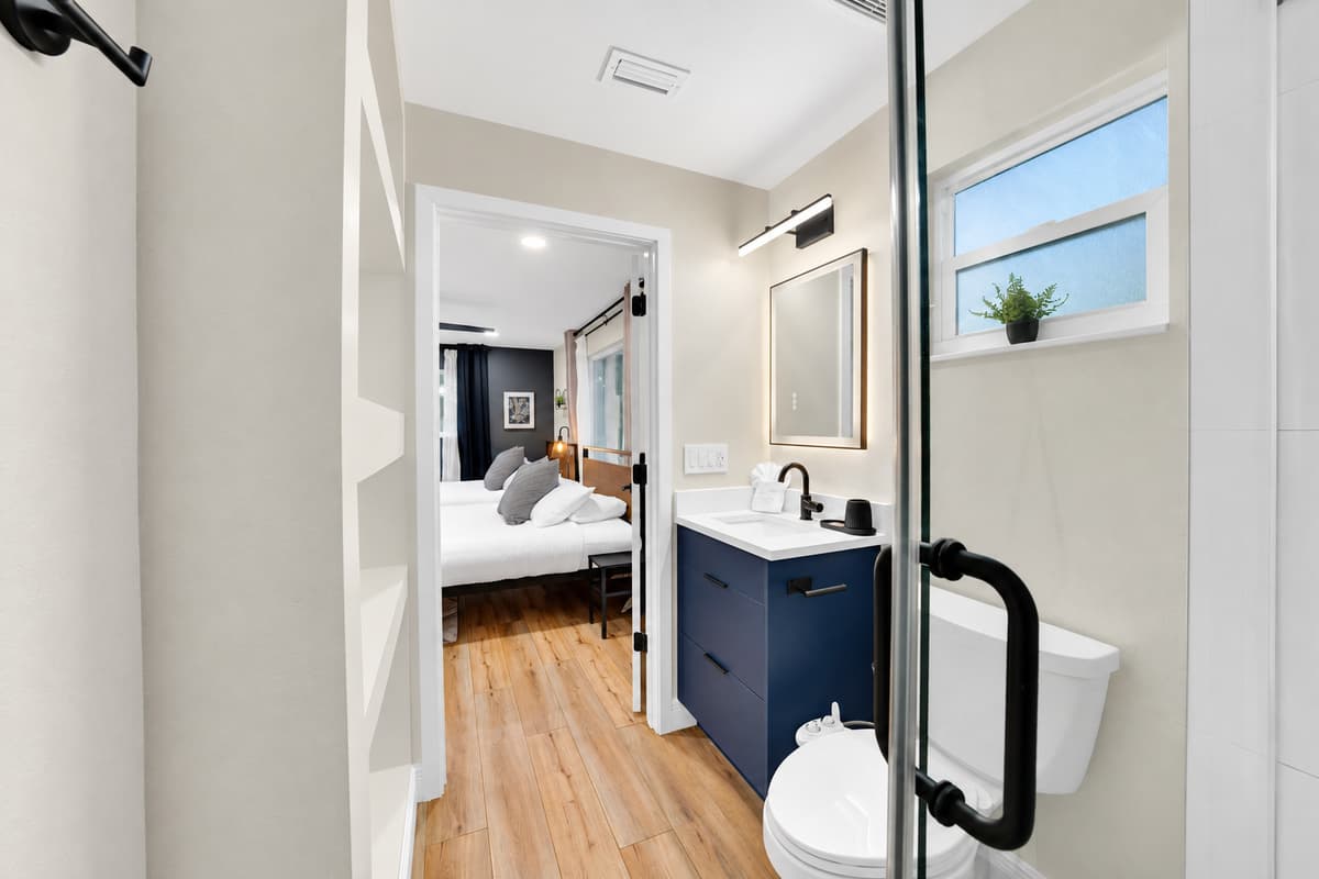 Your bathroom is right there. Nobody else's. Walk-in glass shower and navy vanity opening straight off the bedroom, so mornings start without a queue, a knock, or a walk down the hall in a towel.