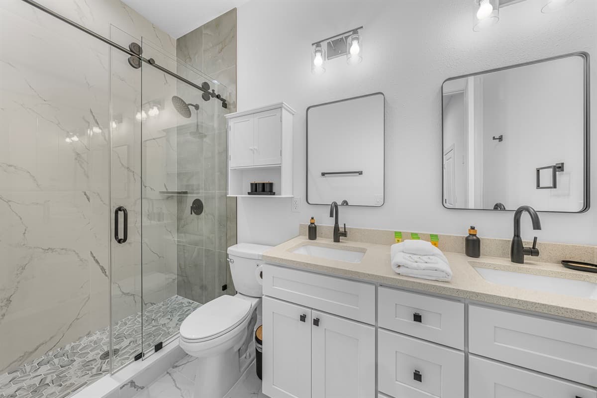 Modern bathroom with glass walk-in shower, dual vanity, and sleek contemporary finishes.