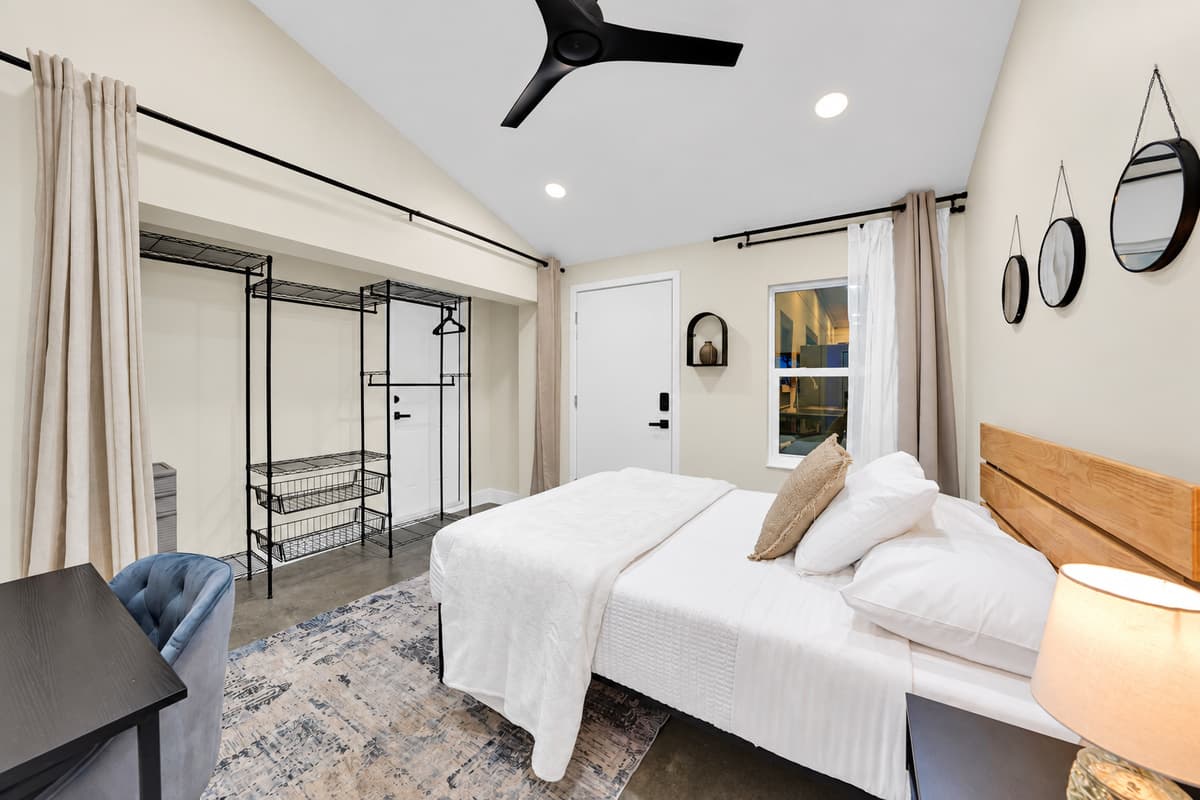 Two beds, full closet, room to actually settle in. Built-in hanging space beside the desk means a week of clothes goes away on day one, and the floor stays clear for the rest of the stay.