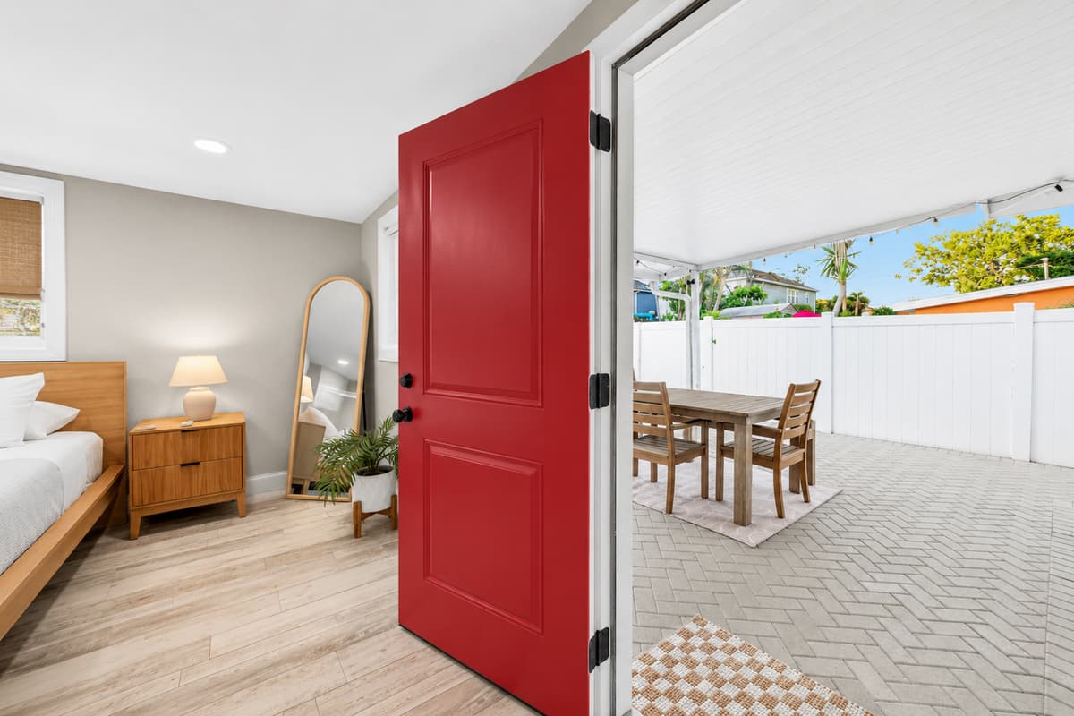 Bedroom with direct access to the outdoor patio through a distinctive red door, creating convenient indoor-outdoor living.
