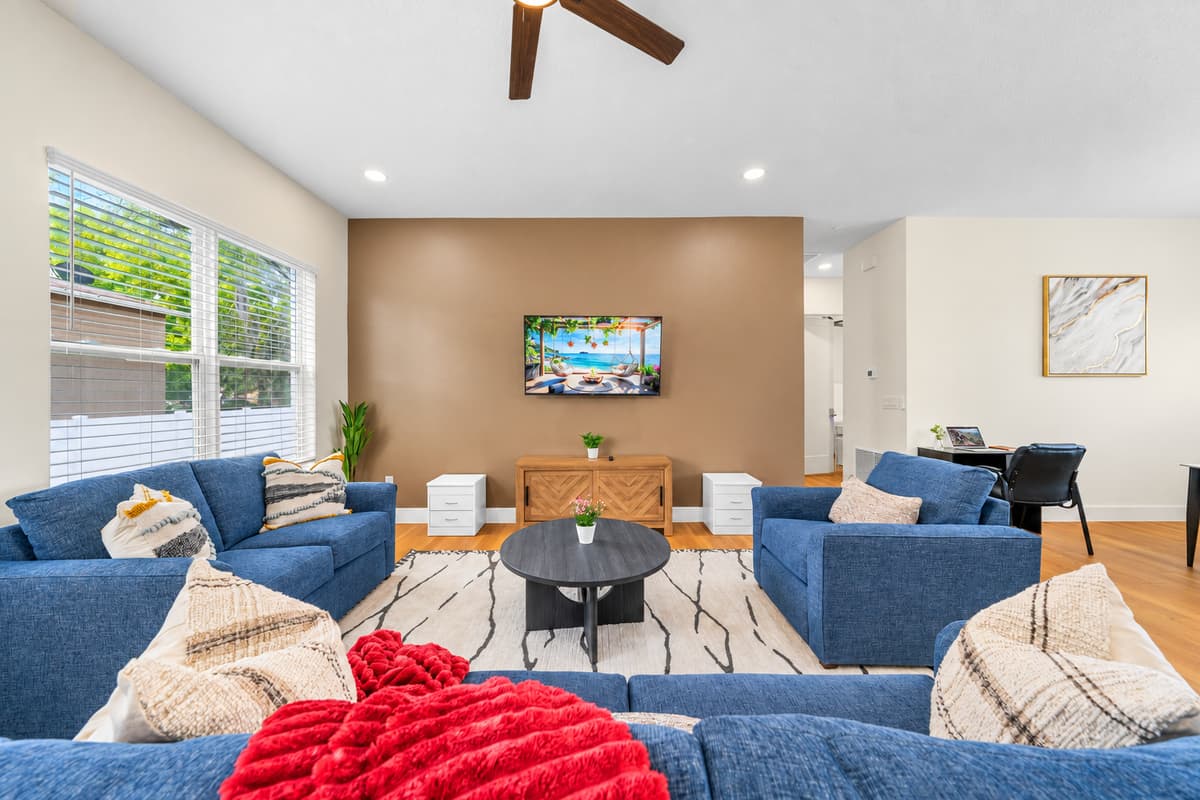 Bright living room with group seating and a smart TV, connected to the dining area and kitchen. Your private ground-floor apartment sleeps up to 8.