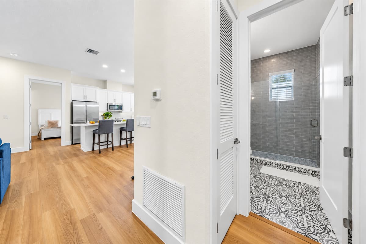 A layout that just makes sense. From the hallway you see the shower, the open kitchen, and the living room beyond. Short walks between rooms and clear floors make moving around with a group feel easy.