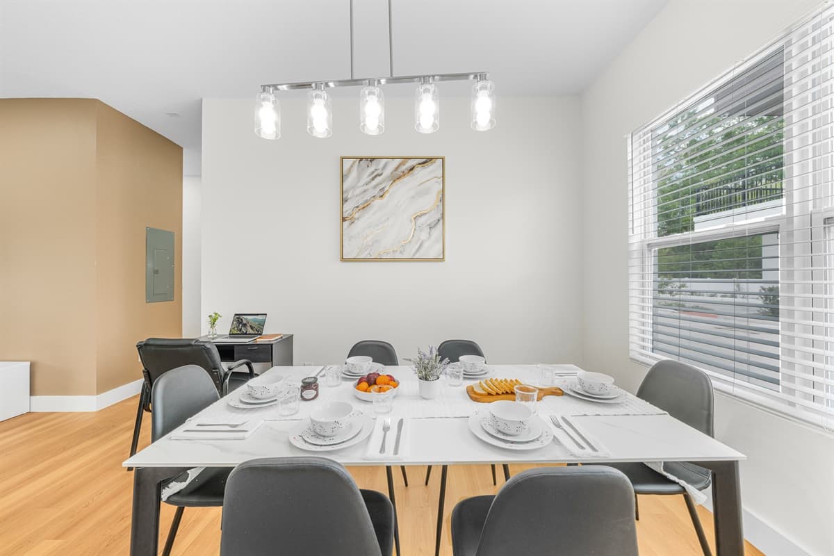 Gather around the dining table, set for a home-cooked meal under stylish pendant lighting.